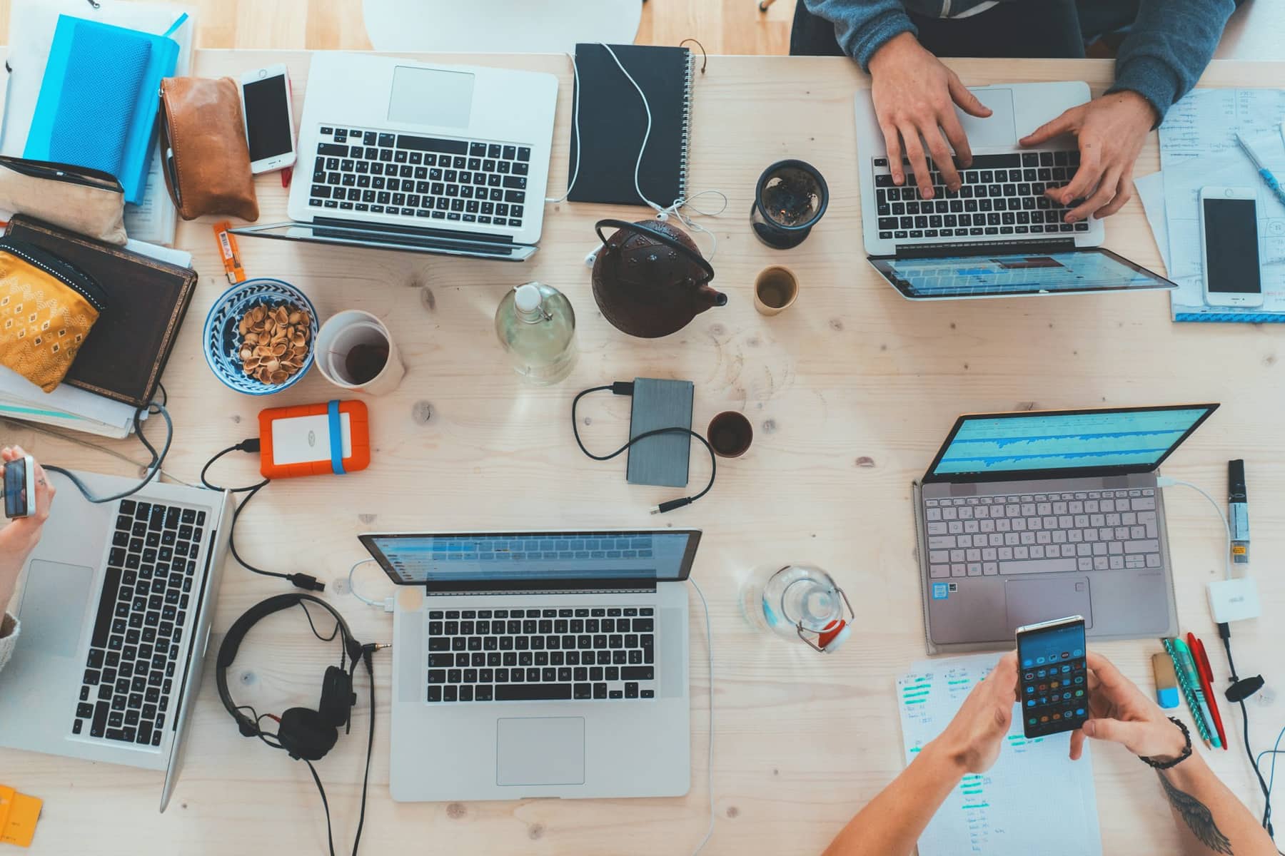 Product team collaborating on laptops and phones around a shared desk